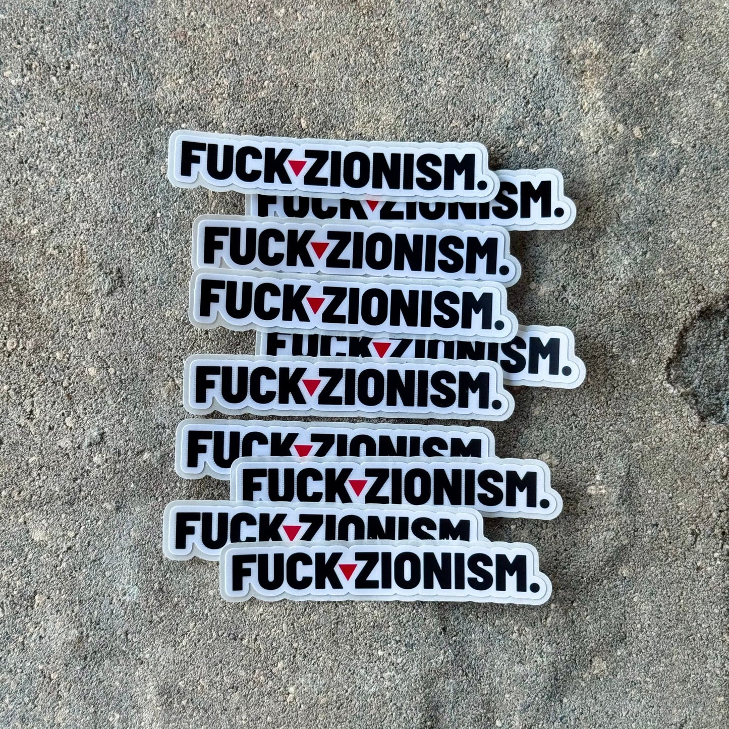Multiple stickers with 'FUCK ZIONISM' text on a concrete surface