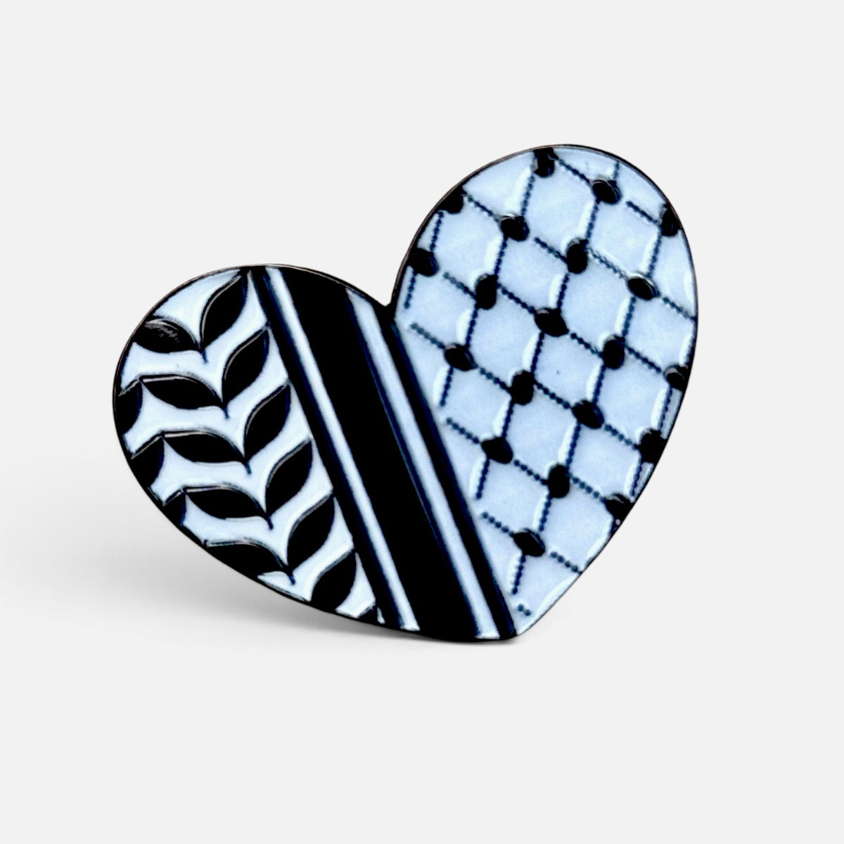 Silenced Roots heart-shaped enamel pin featuring a black and white Palestinian keffiyeh pattern