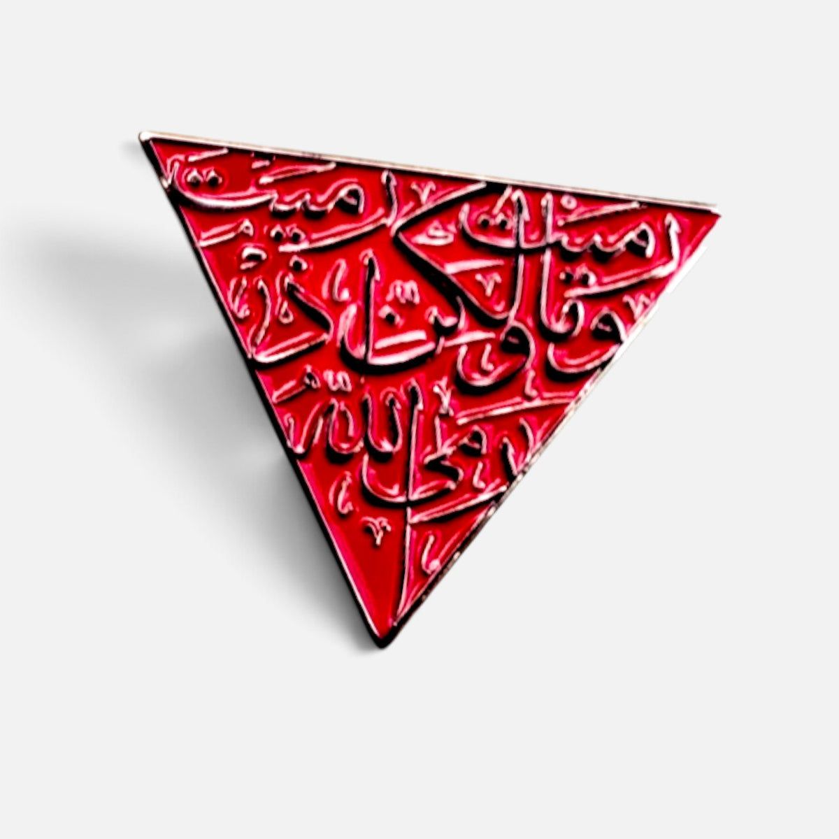 Silenced Roots red enamel triangle pin featuring intricate black Arabic calligraphy as a symbol of resistance.